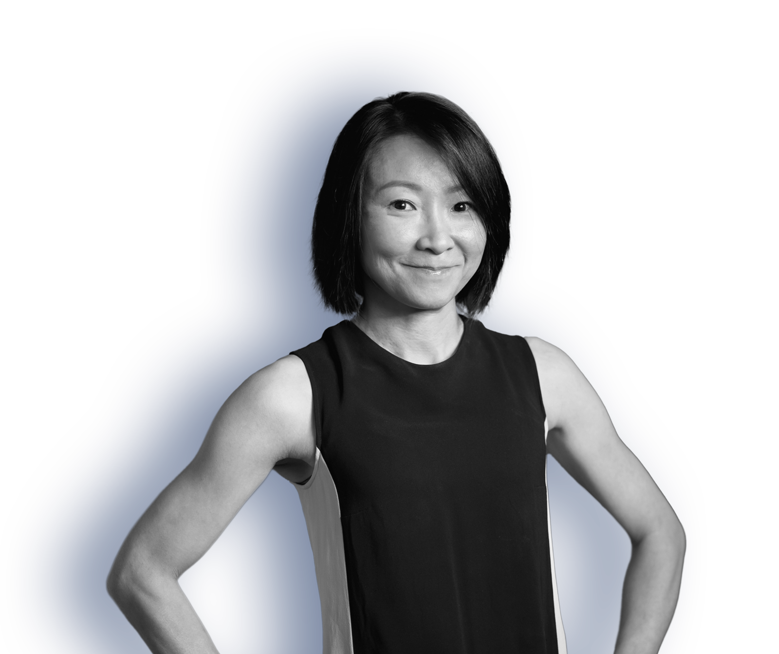 A woman in a black tank top with short hair stands with her hands on her hips.